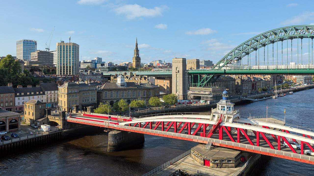 The red and white Swing Bridge over the River Tyne, with the Tyne Bridge and Newcastle city centre behind