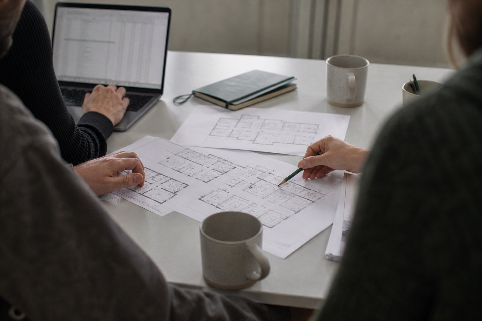 People around a table reviewing floor plans and a spreadsheet for a student scheme